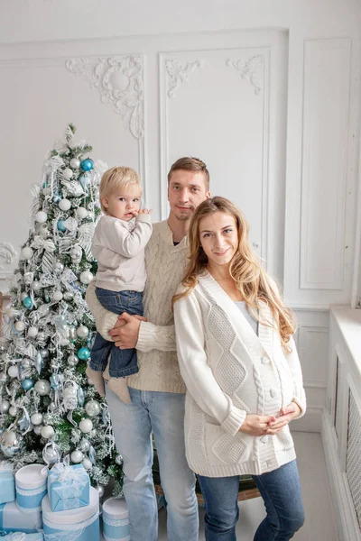 Mutlu aile portresi içinde ana - baba, hamile anne ve küçük oğulları. Yeni Yılınız Kutlu Olsun. süslü Noel ağacı. Noel sabahı parlak oturma odasında. — Stok fotoğraf