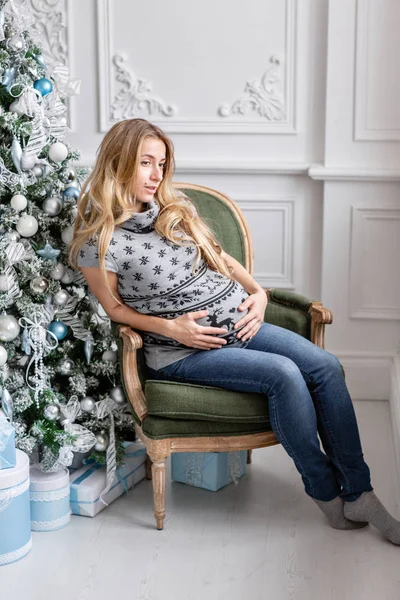 Porträt junge schwangere Mutter. Frohes neues Jahr. geschmückter Weihnachtsbaum. Weihnachtsmorgen im hellen Wohnzimmer. — Stockfoto