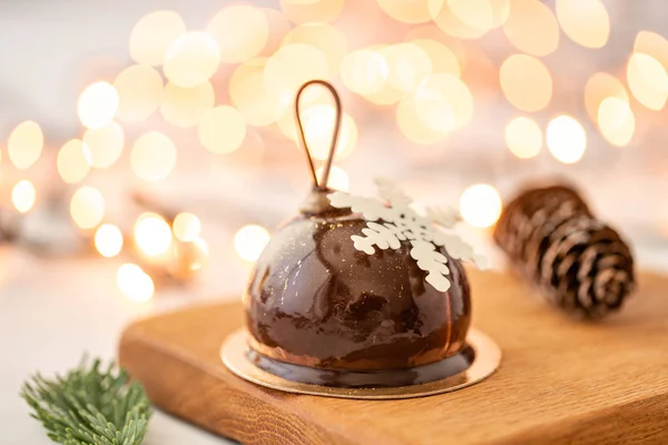 Mini-Moussegebäck-Dessert mit Schokolade glasiert. Girlandenlampen bokeh auf dem Hintergrund. moderner europäischer Kuchen. Französische Küche. Weihnachtsthema. Schneeflocke — Stockfoto