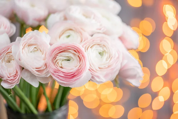 Perzisch buttercup. Bos bleke roze ranunculus bloemen in glasvaas. Garland bokeh op achtergrond. Horizontale Wallpaper — Stockfoto