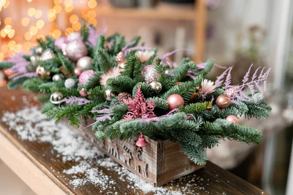 Belo arranjo festivo de abeto fresco, ornamentais rosa em uma caixa de caixa de madeira rústica. Humor de Natal. Garland bokeh em segundo plano . — Fotografia de Stock