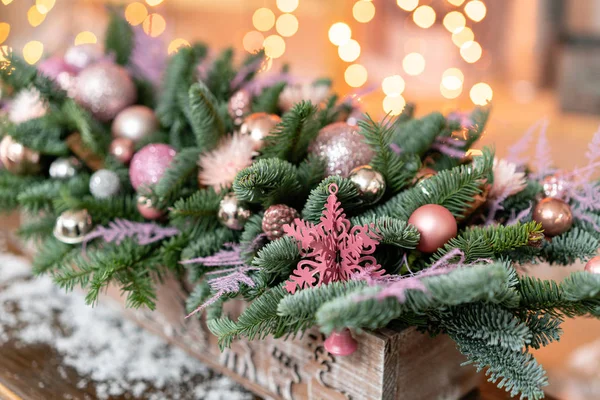 Bir rustik ahşap kutu kutu içinde taze çam, pembe süsbitkileri güzel Festival aranjman. Noel ruh. Garland bokeh arka plan üzerinde.