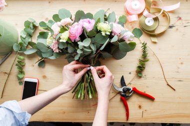 El profesyonel çiçekçi bir buket pembe Düğünçiçeği ve peonies bir çiçekçide yapma Close-up. Düzenleme ve buket ambalaj. Kavram çiçek satışı ve online mağaza