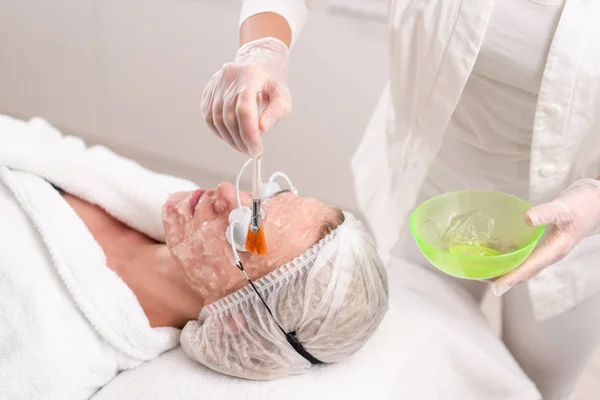 De arts geldt een speciale gel aan de patiënt. Anti acne fototherapie met professionele apparatuur. Mooie vrouw tijdens foto verjonging procedure. Huidbehandeling van gezicht bij cosmetische kliniek. — Stockfoto