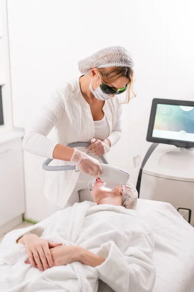 Anty Fototerapia trądziku z profesjonalnego sprzętu. Piękna kobieta w salonie piękności podczas procedury odmładzania zdjęcie. Laserowe leczenie skóry twarzy w klinice kosmetycznej. Sprzęt kosmetyczny, narzędzia — Zdjęcie stockowe