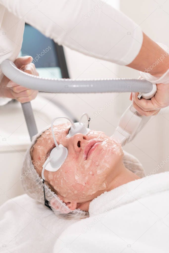 Anti acne phototherapy with professional equipment. Beautiful woman in beauty salon during photo rejuvenation procedure. Laser face skin treatment at cosmetic clinic. Hardware cosmetology