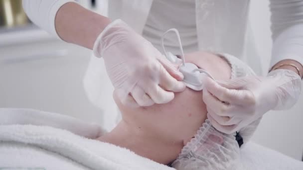 El médico pone las gafas de paciente. Fototerapia anti acné con equipo profesional. Hermosa mujer en el salón de belleza durante el procedimiento de rejuvenecimiento de fotos. Tratamiento de la piel de la cara en clínica cosmética . — Vídeo de stock