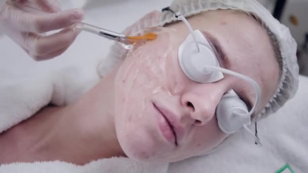 Läkaren gäller en speciell gel för patienten. Anti acne ljusbehandling med professionell utrustning. Vacker kvinna under foto föryngring förfarandet. Ansikte hudbehandling på kosmetiska klinik. — Stockvideo