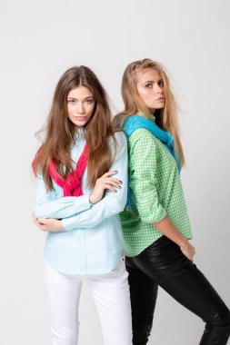 mutlu kız kadın gömlek ve bir kazak onun omuzlarında. İki kız kardeş moda bahar görüntüsü. Renkler renkli kıyafetler. Modelleri ile sarışın ve ışık kahverengi saç. Kameraya bakarak ve gülümseyen.
