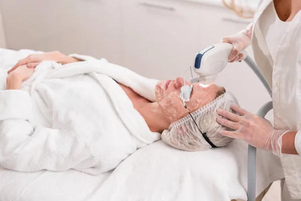 Fototerapia anti acne com equipamento profissional. Mulher bonita no salão de beleza durante o procedimento de rejuvenescimento de fotos. Tratamento da pele do rosto do laser na clínica cosmética. Cosmetologia de hardware — Fotografia de Stock