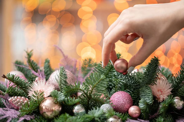 Genç kadın oluşturur ve taze Ladin, süsbitkileri bir rustik ahşap kutu kutu içinde güzel Festival düzenleme süsler. Noel ruh. Garland bokeh arka plan üzerinde.