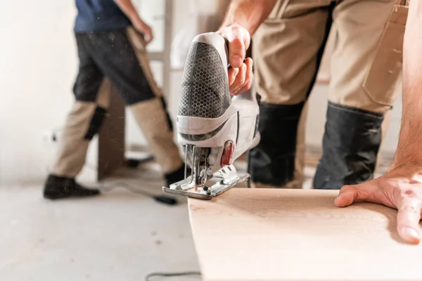 Hombre trabajador corta la placa laminada con una sierra electrostática. la instalación de nuevos pisos laminados de madera. concepto de reparación en casa . — Foto de Stock