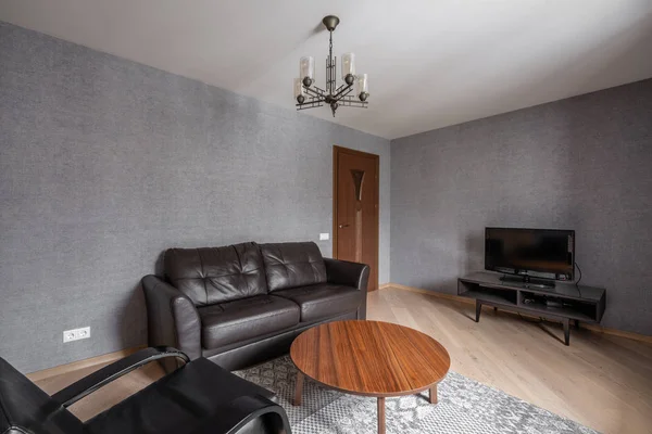 俄罗斯, 下诺夫哥罗德-2018年1月10日, 2018年1月10日: 私人公寓。现代化的客厅配有真皮沙发、扶手椅、木制咖啡桌和舒适的沙发和灯具上的电视枕头。室内设计 — 图库照片