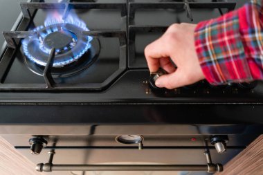ateşe odaklan. Gaz ocakla aracılığıyla otomatik elektrikli ateşleme aydınlatma bir adam. Modern gaz yakıcı ve hob bir mutfak grubu hakkında. Koyu siyah renkli ve modern bir dairede ahşap küçük mutfak