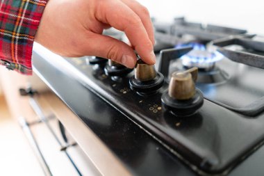 Gaz ocakla aracılığıyla otomatik elektrikli ateşleme aydınlatma bir adam. Modern gaz yakıcı ve hob bir mutfak grubu hakkında. Koyu siyah renkli ve modern bir dairede ahşap küçük mutfak