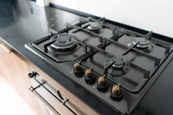 Σύγχρονο καυστήρα αερίου και εστίες μαγειρέματος για μια σειρά κουζινών. Σκούρο μαύρο χρώμα και ξύλινη μικρή κουζίνα σε ένα μοντέρνο διαμέρισμα — Φωτογραφία Αρχείου