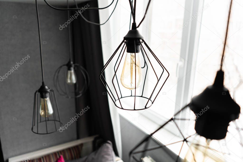 loft style iron lampshade with a light bulb in the interior living room in modern apartment. Vintage style light bulbs. glass round bulbs with a spiral on wall.