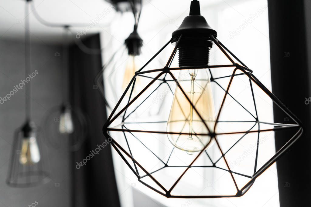 loft style iron lampshade with a light bulb in the interior living room in modern apartment. Vintage style light bulbs. glass round bulbs with a spiral on wall.