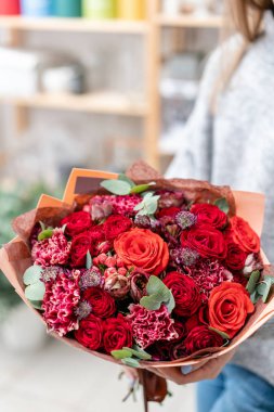 güzel taze karışık çiçekli buket kadın elinde kesilmiş. Çiçekçi Çiçek dükkanında çalışır. Parlak sulu kırmızı renkler