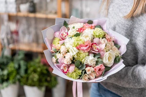 Hermoso ramo fresco cortado de flores mixtas en mano de mujer. el trabajo de la floristería en una florería. Delicado color de tonos pastel — Foto de Stock