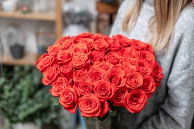 Red roses in glass vases in womens hands. Bunch scarlet red. the concept of a florist in a flower shop. Wallpaper.