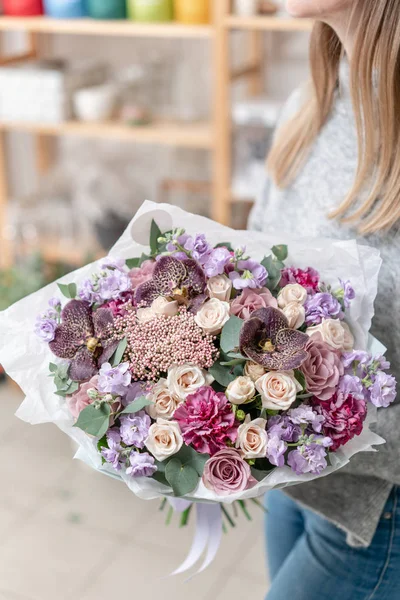 Hermoso ramo fresco cortado de flores mixtas en mano de mujer. el trabajo de la floristería en una florería. Delicado color de tonos pastel — Foto de Stock