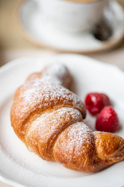 Coffee cappuccino with croissant on white plate in restaurant. Light morning Breakfast, fresh warm pastries and raspberries — Stock Photo, Image