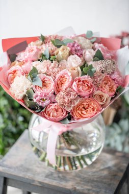 güzel taze ahşap masa üzerinde vazoda karışık çiçekler Buket kesti. . Çiçekçi Çiçek dükkanında çalışır. Hassas Pastel tonları renk