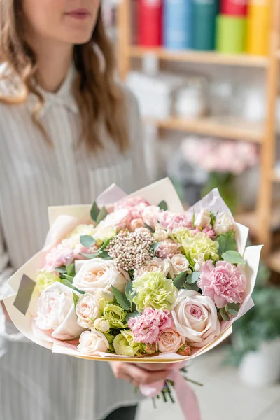 Hermoso ramo fresco cortado de flores mixtas en mano de mujer. el trabajo de la floristería en una florería. Delicado color de tonos pastel — Foto de Stock