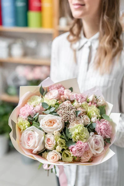 Hermoso ramo fresco cortado de flores mixtas en mano de mujer. el trabajo de la floristería en una florería. Delicado color de tonos pastel — Foto de Stock