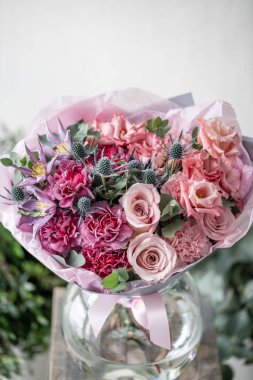 güzel taze ahşap masa üzerinde vazoda karışık çiçekler Buket kesti. . Çiçekçi Çiçek dükkanında çalışır. Hassas Pastel tonları renk