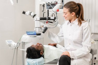 Kadın dişçi Gelişmiş Kullanıcı, diş araçları. Mikroskop lense hasta dişlerini incelenirken arıyorum. Diş Kliniği ofisinde. Tıp, diş hekimliği ve sağlık kavramı.