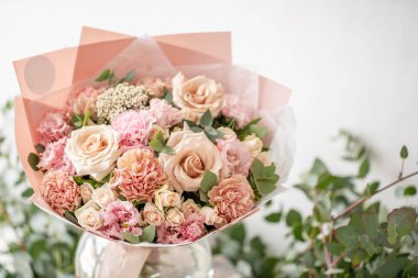 güzel taze ahşap masa üzerinde vazoda karışık çiçekler Buket kesti. Çiçekçi Çiçek dükkanında çalışır. Hassas Pastel tonları renk