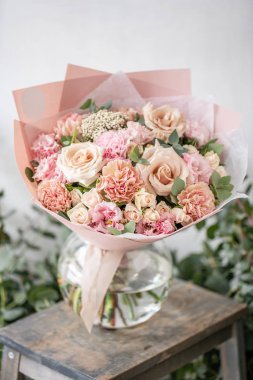 güzel taze ahşap masa üzerinde vazoda karışık çiçekler Buket kesti. Çiçekçi Çiçek dükkanında çalışır. Hassas Pastel tonları renk
