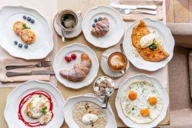 Kahvaltı. Ay çöreği, kahve ve birçok farklı yemekler restoranda masaya. Frittata - İtalyan omleti. Domates, avokado, ıspanak ve peynir omlet.