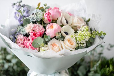 güzel taze ahşap masa üzerinde vazoda karışık çiçekler Buket kesti. Çiçekçi Çiçek dükkanında çalışır. Hassas Pastel tonları renk