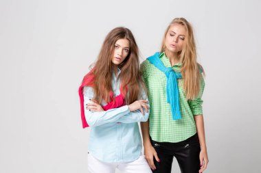 mutlu kız kadın gömlek ve bir kazak onun omuzlarında. İki kız kardeş moda bahar görüntüsü. Renkler renkli kıyafetler. Modelleri ile sarışın ve ışık kahverengi saç. Kameraya bakarak .