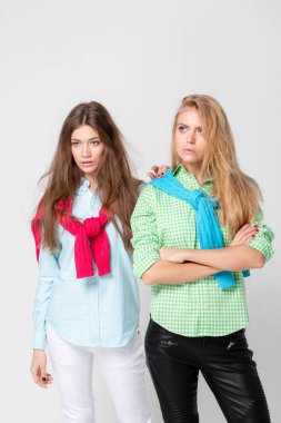 mutlu kız kadın gömlek ve bir kazak onun omuzlarında. İki kız kardeş moda bahar görüntüsü. Renkler renkli kıyafetler. Modelleri ile sarışın ve ışık kahverengi saç. Kameraya bakarak .
