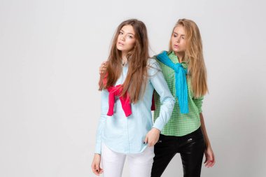 mutlu kız kadın gömlek ve bir kazak onun omuzlarında. İki kız kardeş moda bahar görüntüsü. Renkler renkli kıyafetler. Modelleri ile sarışın ve ışık kahverengi saç. Kameraya bakarak .