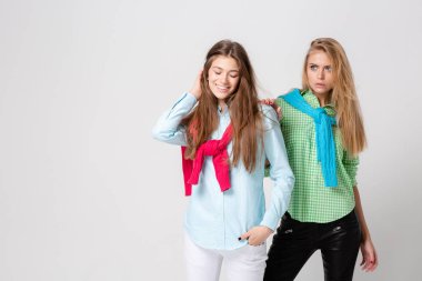mutlu kız kadın gömlek ve bir kazak onun omuzlarında. İki kız kardeş moda bahar görüntüsü. Renkler renkli kıyafetler. Modelleri ile sarışın ve ışık kahverengi saç. Kameraya bakarak .