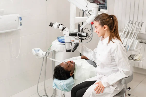 Dentista femenina usuario avanzado, herramientas dentales. Mirando en la lente de un microscopio mientras examina los dientes de sus pacientes. en el consultorio dental. Concepto de medicina, odontología y salud . —  Fotos de Stock