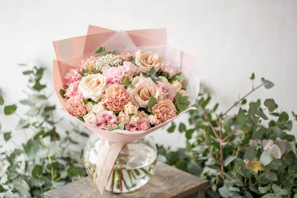 Beau bouquet frais coupé de fleurs mélangées dans un vase sur une table en bois. Le travail du fleuriste dans un magasin de fleurs. Couleur délicate des tons pastel — Photo