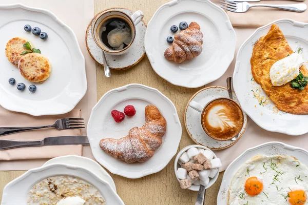 Pequeno-almoço. Croissants, café e muitos pratos diferentes na mesa do restaurante. Frittata - omeleta italiana. Omelete com tomate, abacate, espinafre e queijo mole . — Fotografia de Stock