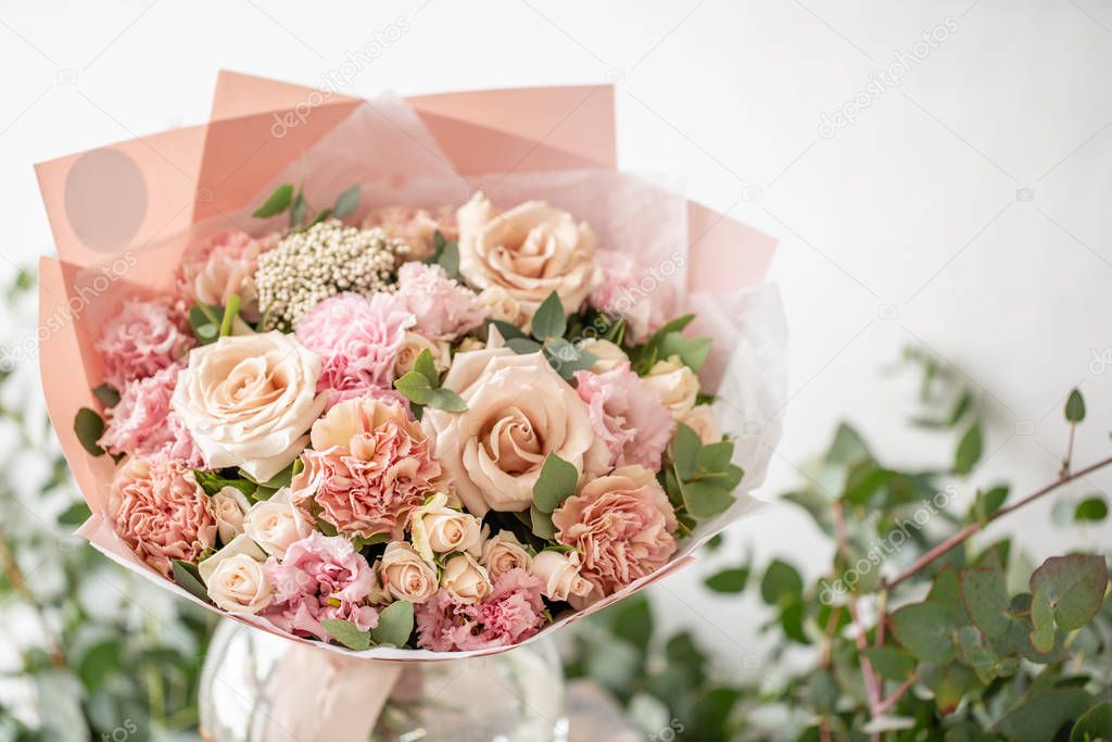 beautiful fresh cut bouquet of mixed flowers in vase on wooden table. The work of the florist at a flower shop. Delicate Pastel tones color