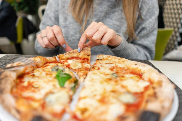 Eine Frau isst neapolitanische Pizza aus dem Holzofen. Mittagessen in einem italienischen Restaurant. Tisch neben einem großen Fenster. Margarita und vier Käse — Stockfoto