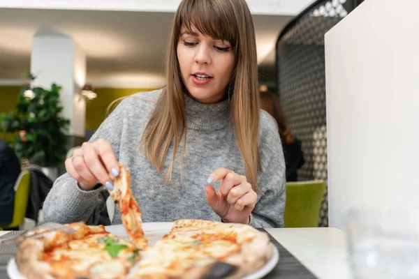 Žena jí neapolskou pizzu z dřevo vypalování kamna. oběd v italské restauraci. Tabulka blízko velké okno. Markéta a čtyři sýr — Stock fotografie