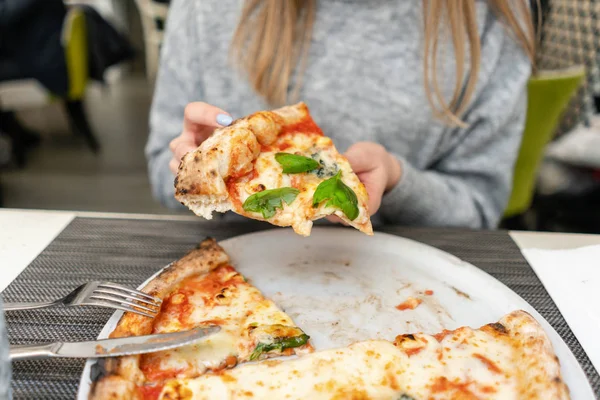 Eine Frau isst neapolitanische Pizza aus dem Holzofen. Mittagessen in einem italienischen Restaurant. Tisch neben einem großen Fenster. Margarita und vier Käse — Stockfoto