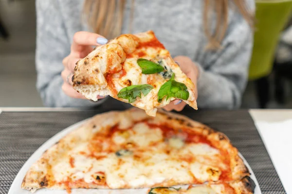 Bir kadın odun yanan soba Napoliten pizza yiyor. bir İtalyan restoranında öğle yemeği. Tablo büyük bir pencere yakınında. Margarita ve dört peynir