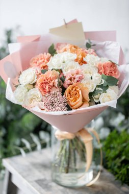 güzel taze ahşap masa üzerinde vazoda karışık çiçekler Buket kesti. Çiçekçi Çiçek dükkanında çalışır. Hassas Pastel tonları renk