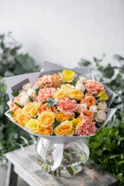 güzel taze ahşap masa üzerinde vazoda karışık çiçekler Buket kesti. Çiçekçi Çiçek dükkanında çalışır. Hassas Pastel tonları renk